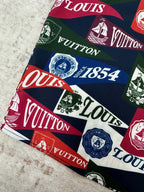 Short-sleeve shirt fabric close-up with multicolor Louis Vuitton crest and logo print