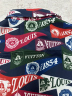 Short-sleeve shirt laid flat showing bold multicolor Louis Vuitton crest and logo pattern
