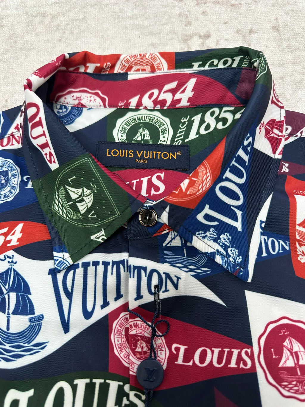 Close-up of short-sleeve shirt collar with multicolor Louis Vuitton crest and logo print