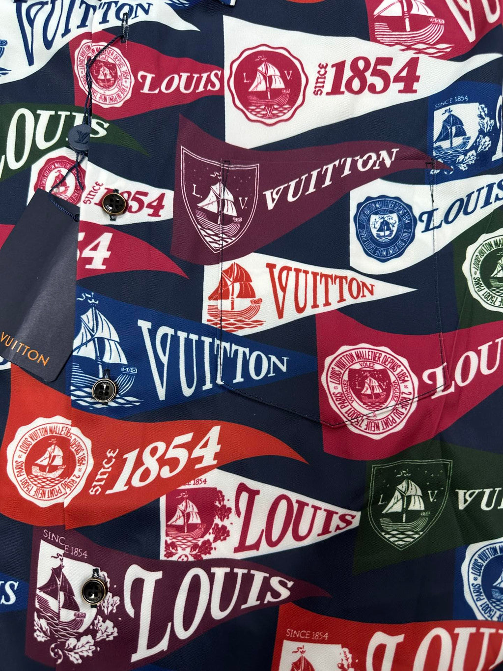 Short-sleeve shirt fabric close-up with multicolor Louis Vuitton logo, crest, and number motifs
