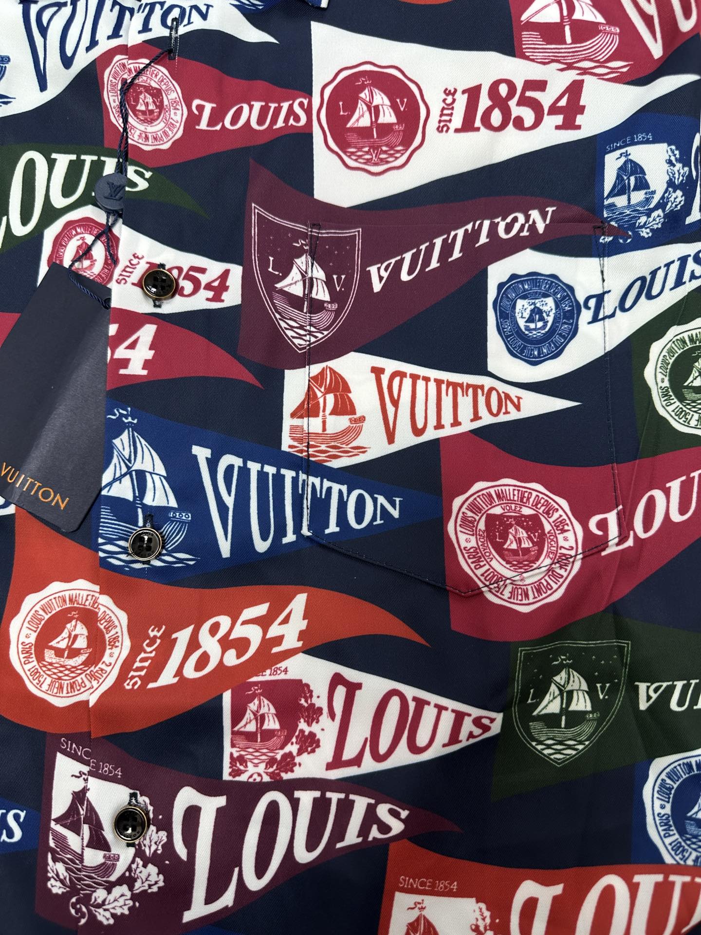 Short-sleeve shirt fabric close-up with multicolor Louis Vuitton logo, crest, and number motifs