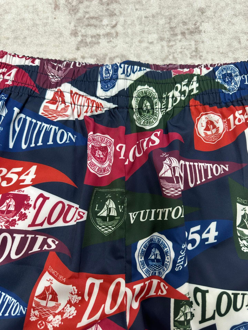 Multicolor patterned shorts fabric with Louis Vuitton text and 1854 crests
