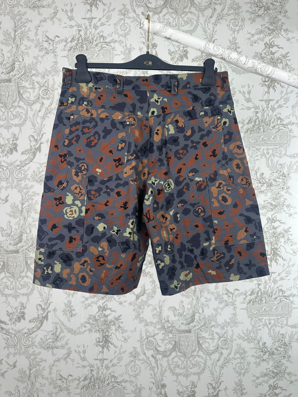 Men's patterned shorts with multicolor camo print, shown front on hanger