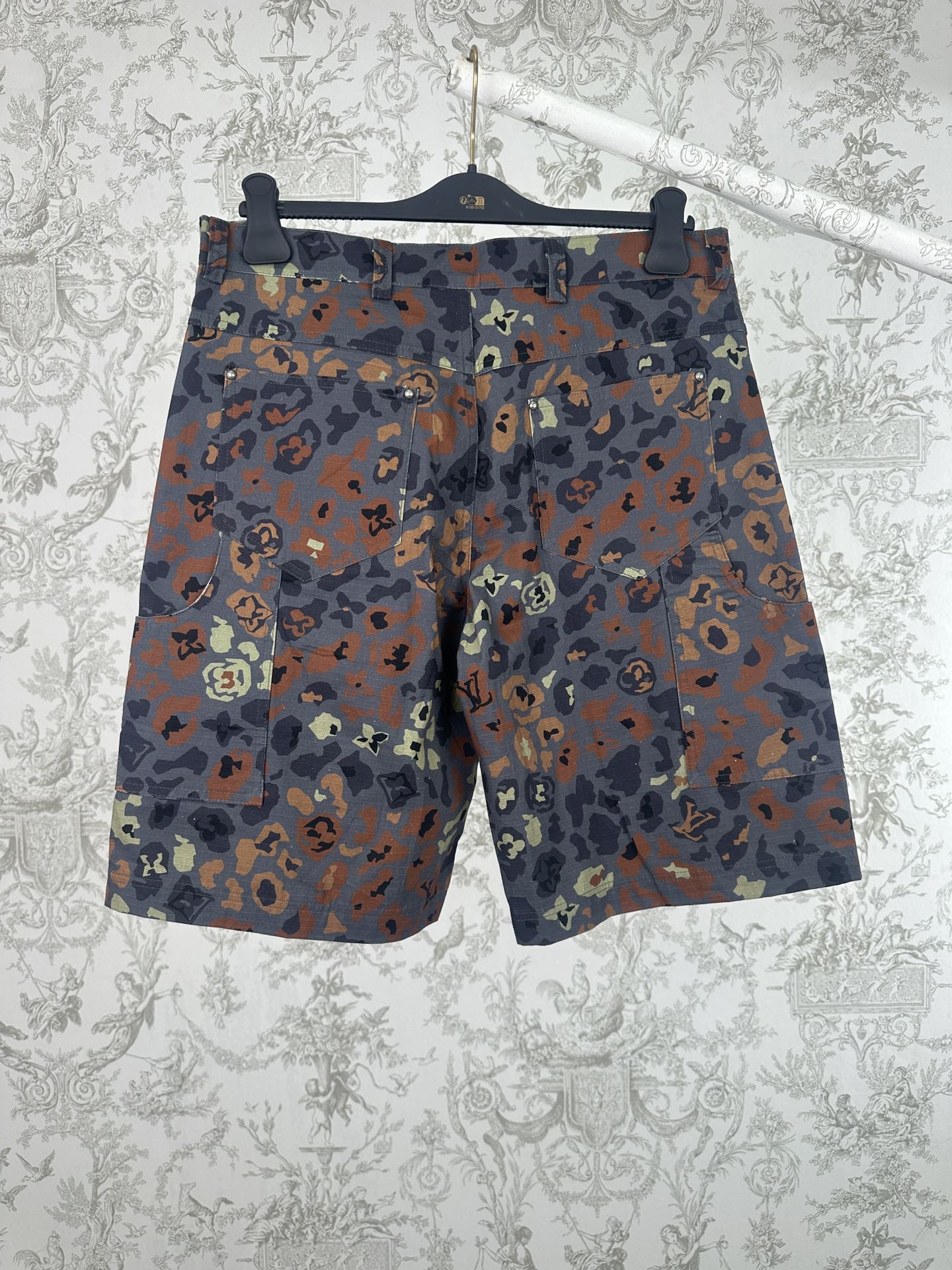 Men's patterned shorts with multicolor camo print, shown front on hanger