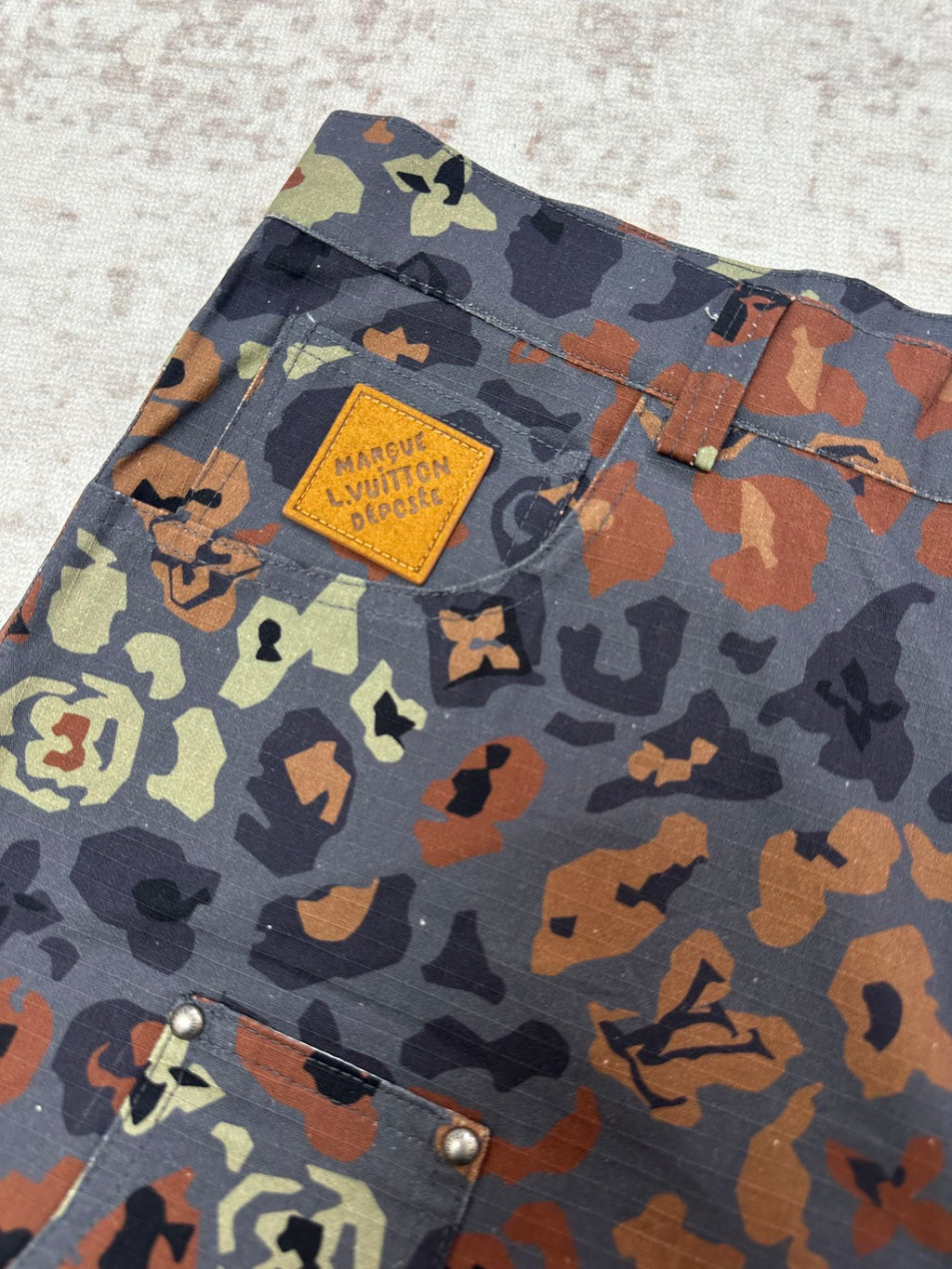 Patterned shorts fabric with Louis Vuitton patch label near the upper pocket