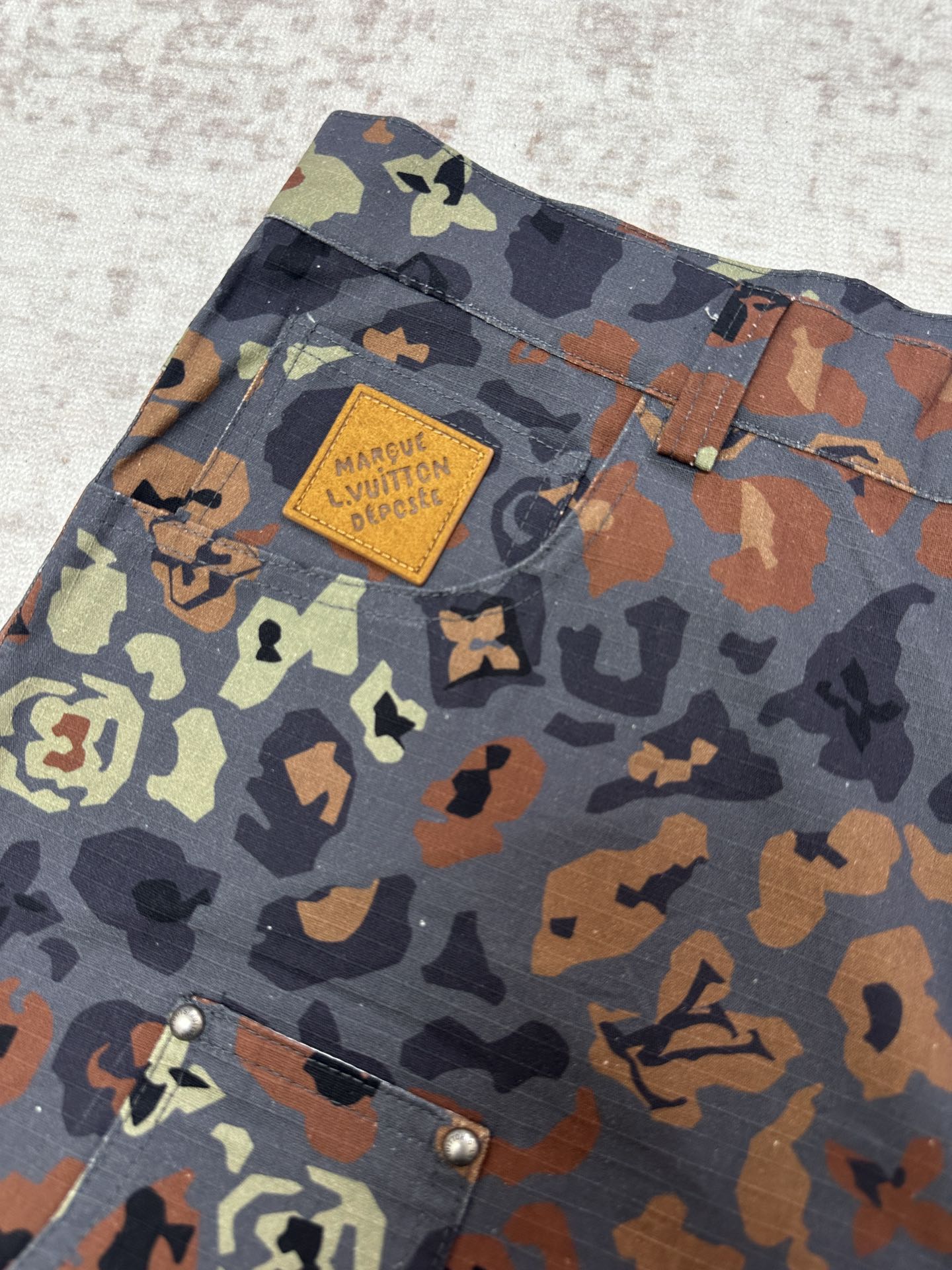 Patterned shorts fabric with Louis Vuitton patch label near the upper pocket