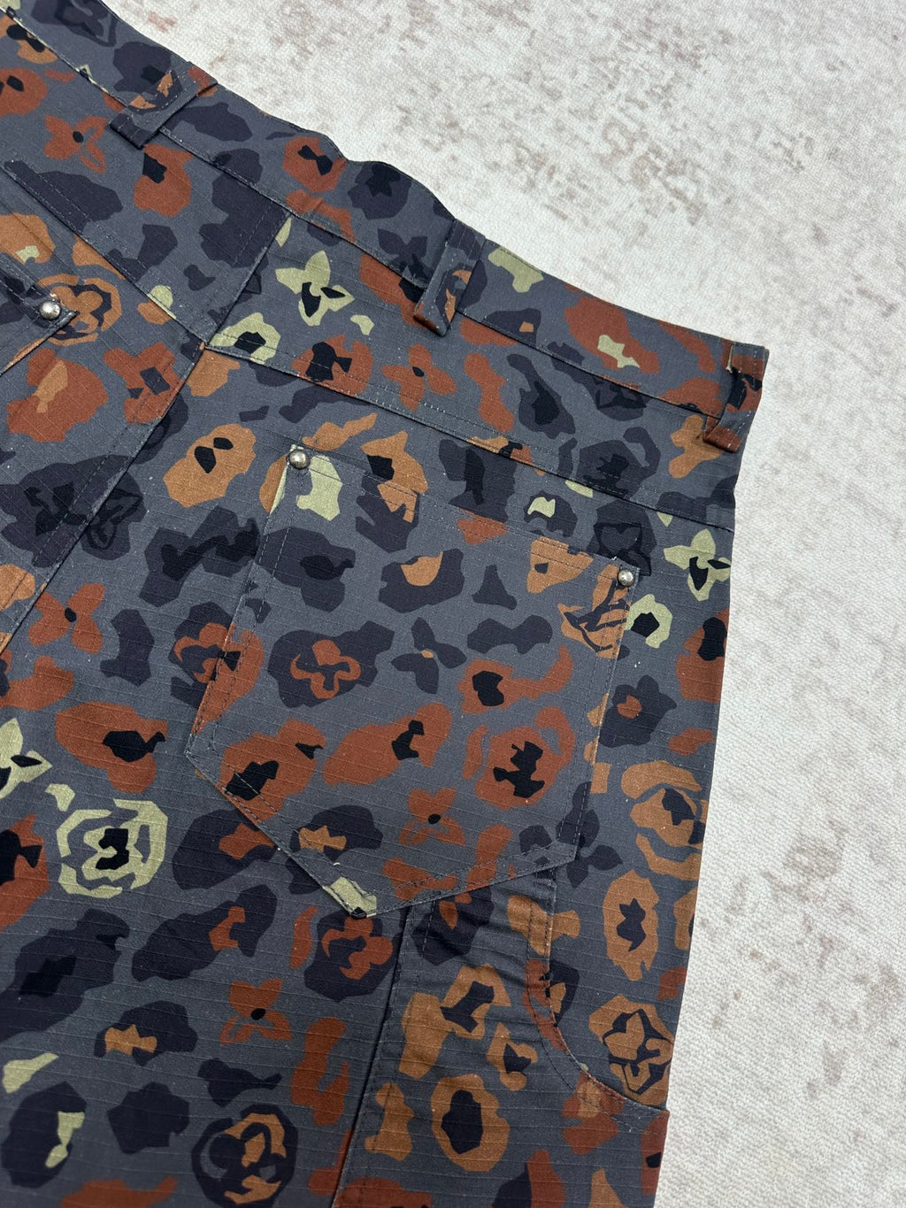 Patterned shorts front corner with belt loops, button details, and pockets