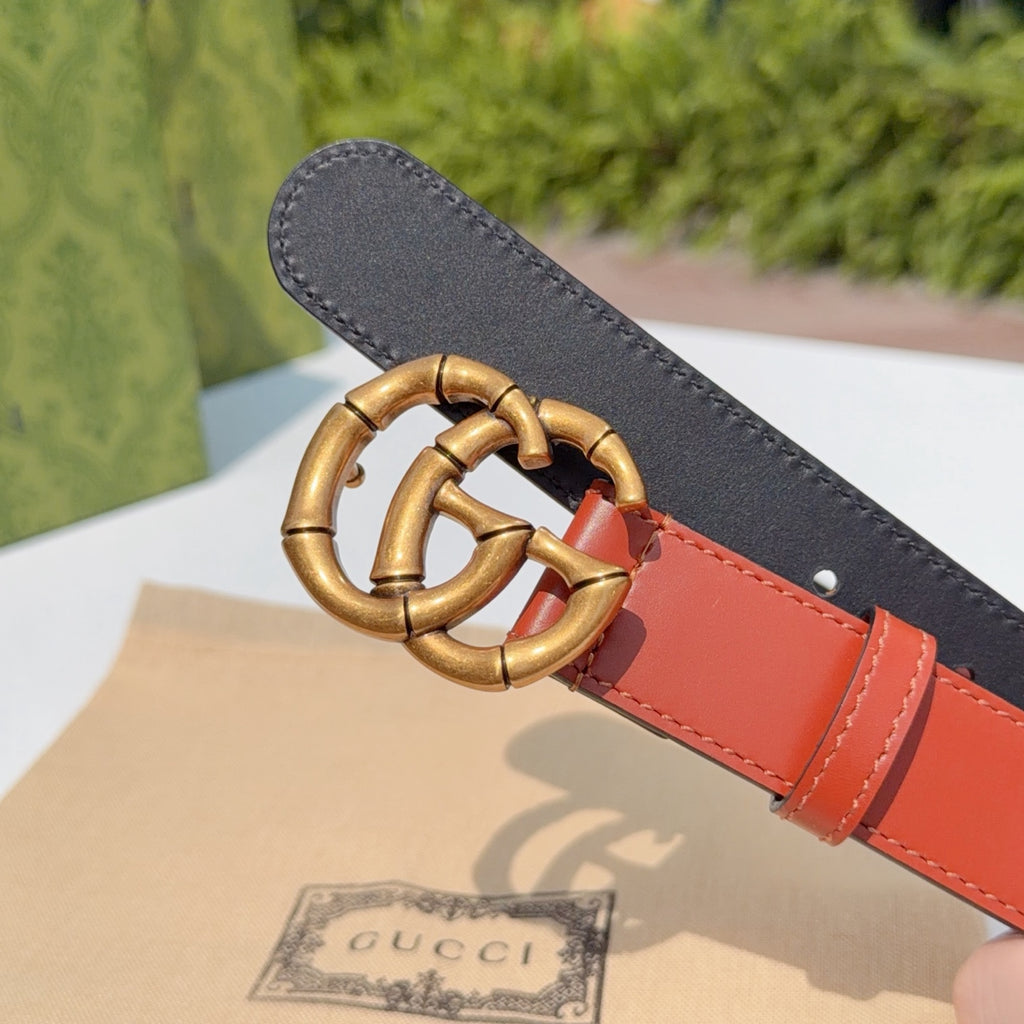 Gucci belt with black textured back, red leather front, and gold buckle