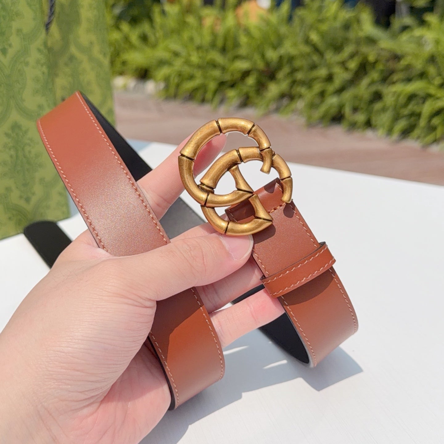 Tan leather belt with large gold-tone buckle, end detail