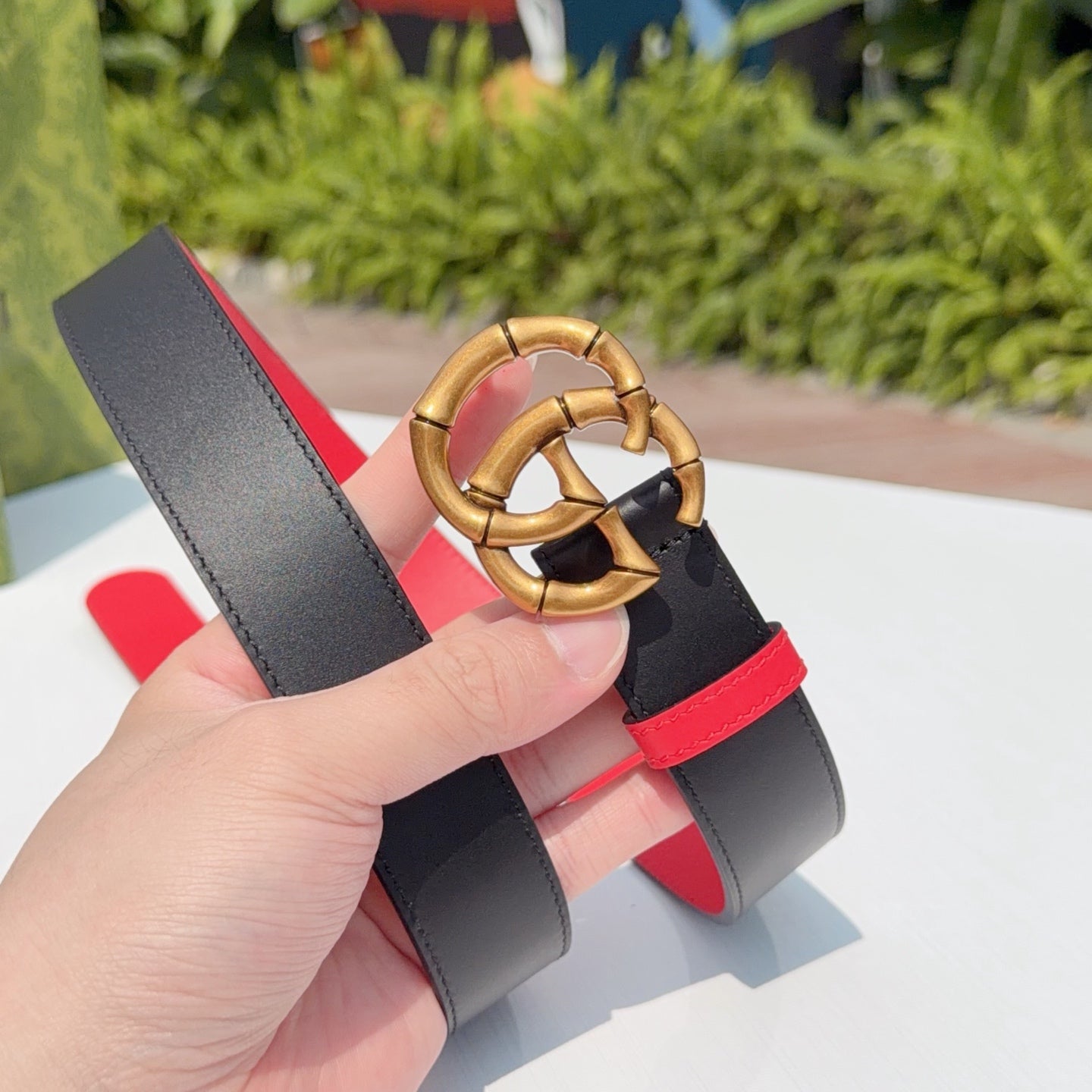 Gucci leather belt close-up of gold double-G buckle on black leather with red lining