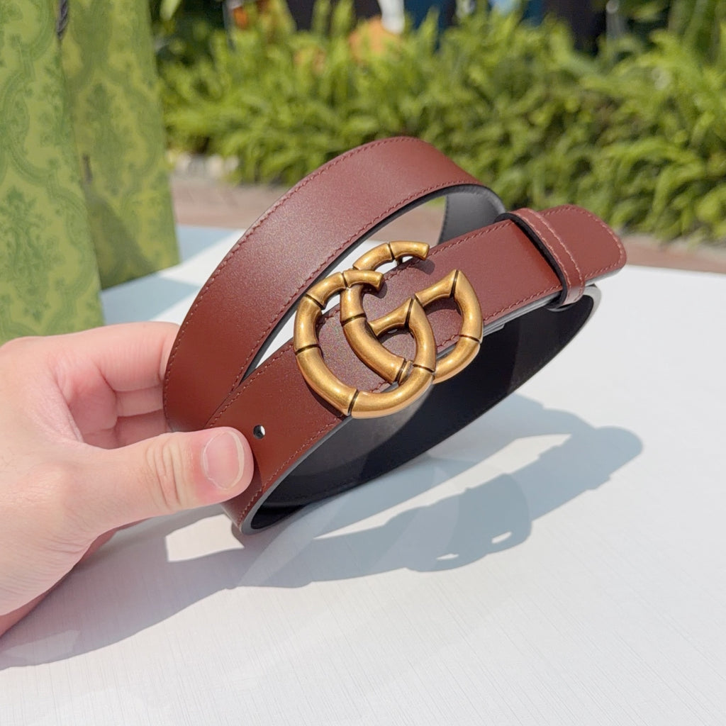 Gucci belt close-up: gold interlocking buckle on maroon leather strap