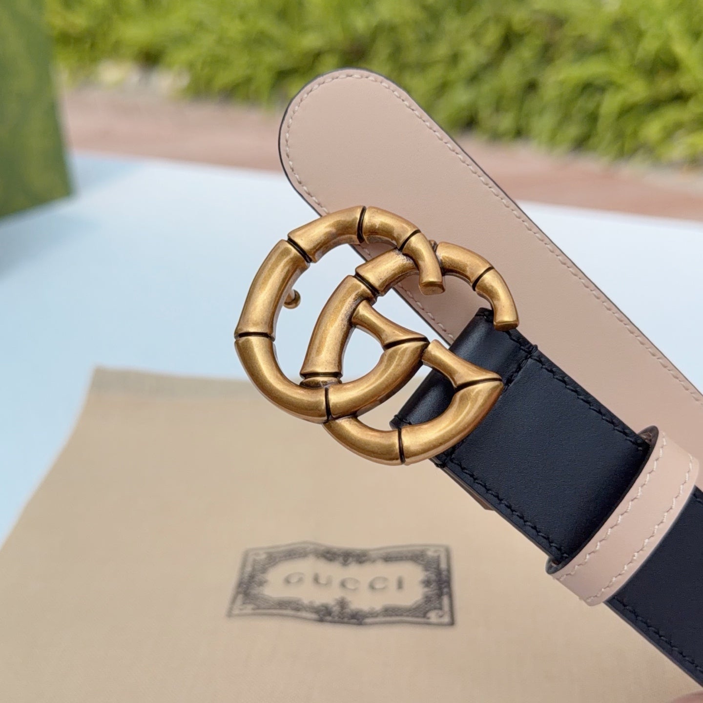 Gucci belt buckle close-up with gold-tone hardware and tan underside on dark leather