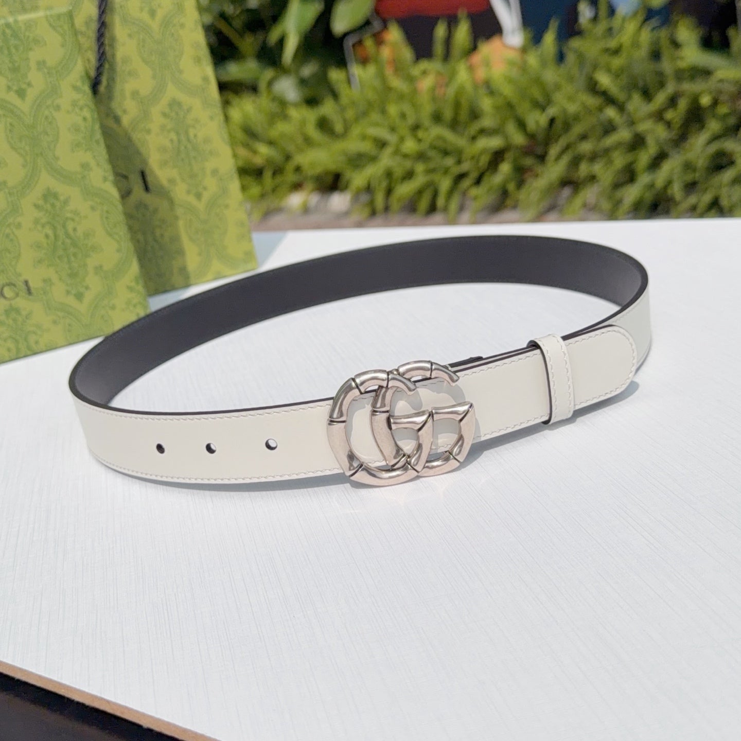 Cream leather belt with silver-tone double G buckle and punched holes, adjustable strap