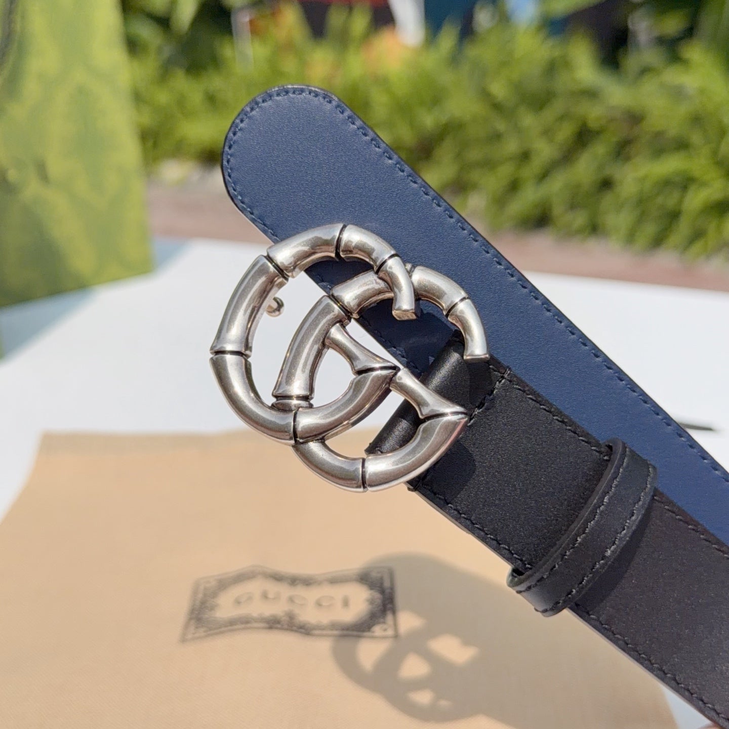 Leather belt with silver double-G buckle, dark strap with blue underside