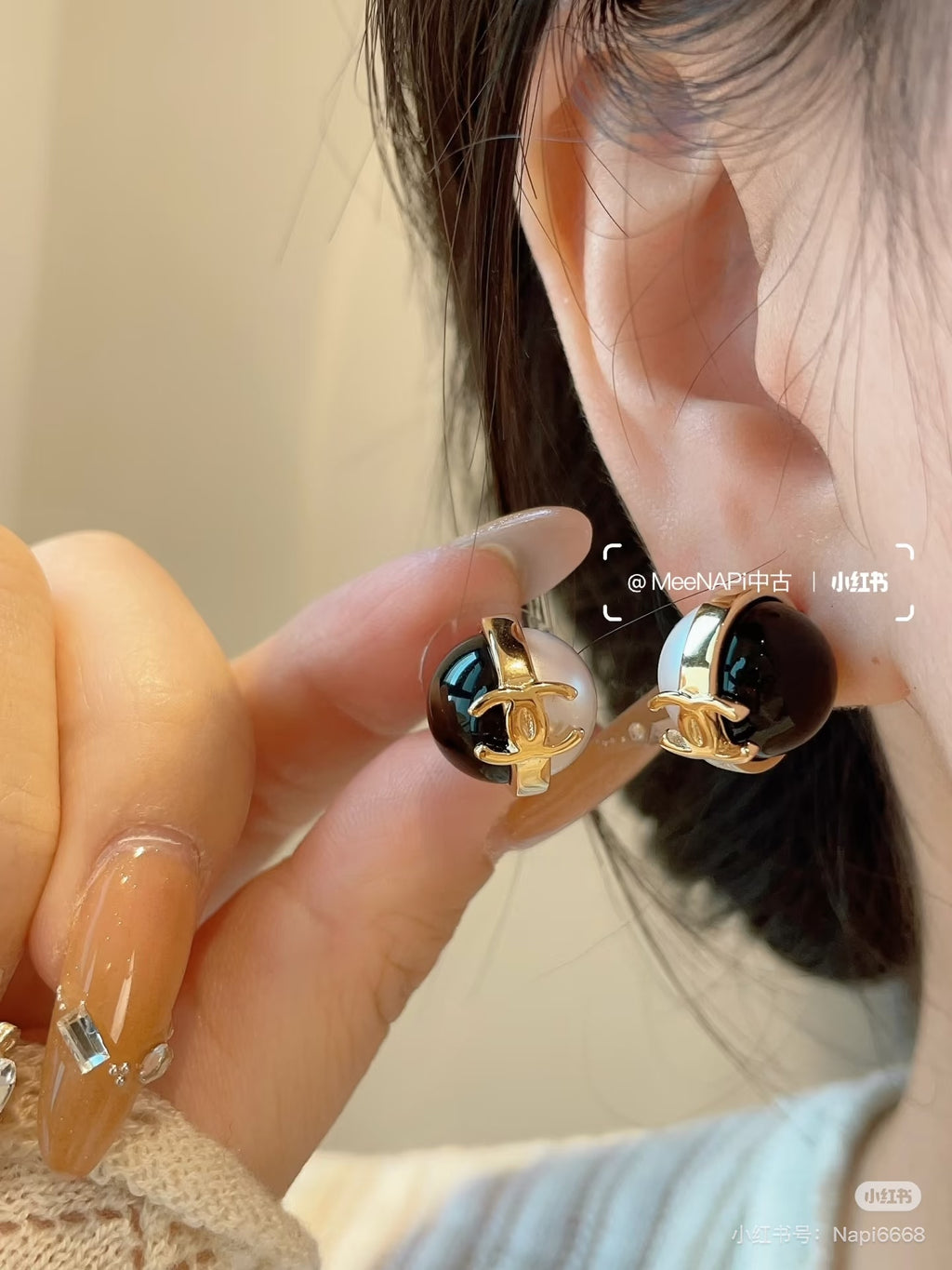 Chanel CC earrings on a wearer: gold-tone and black enamel with white faux pearl detail
