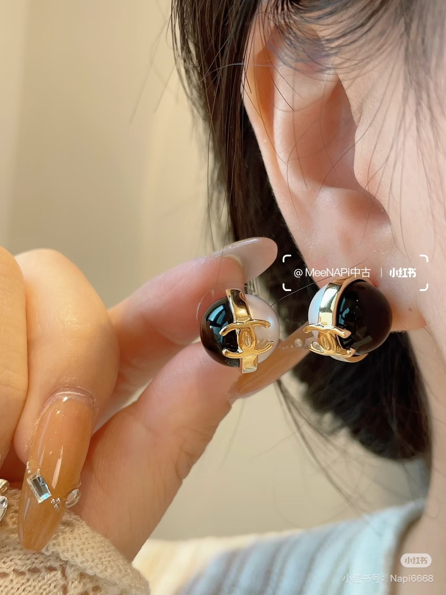 Chanel CC earrings on a wearer: gold-tone and black enamel with white faux pearl detail