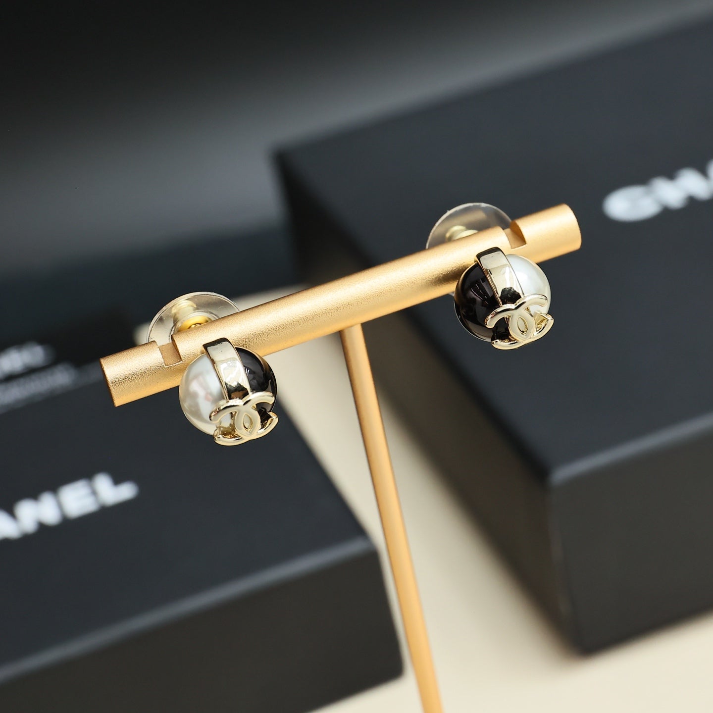 Pair of Chanel stud earrings with gold-tone CC and white faux pearl accents on black
