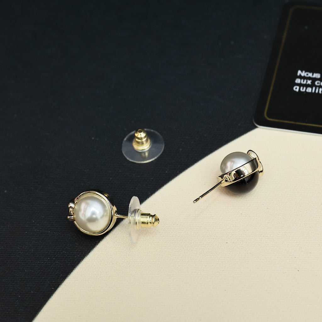 Chanel stud earrings with gold-tone backs, faux pearl fronts, and CC emblem