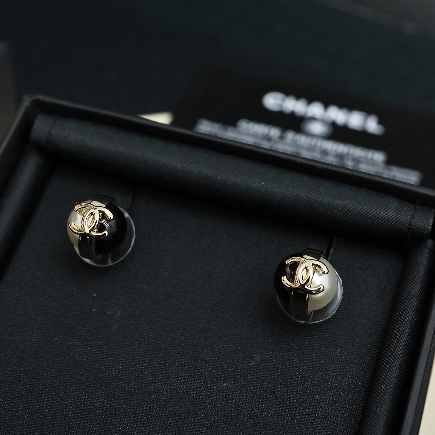Pair of Chanel stud earrings with gold-tone CC and white faux pearls on black base