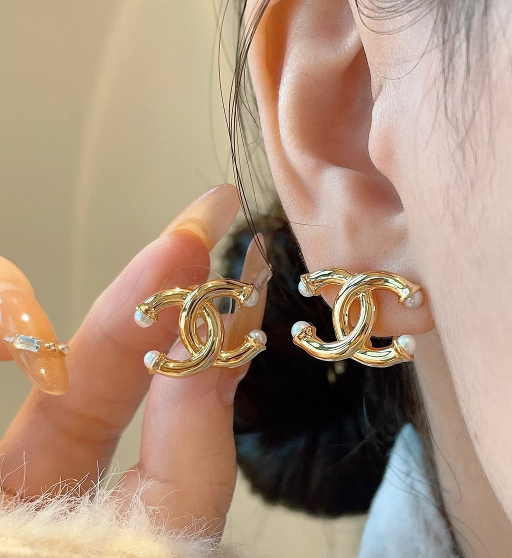 Chanel gold-tone CC logo earrings on ear with pearl-like bead accents