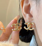 Chanel gold-tone CC logo earrings on ear with pearl-like bead accents