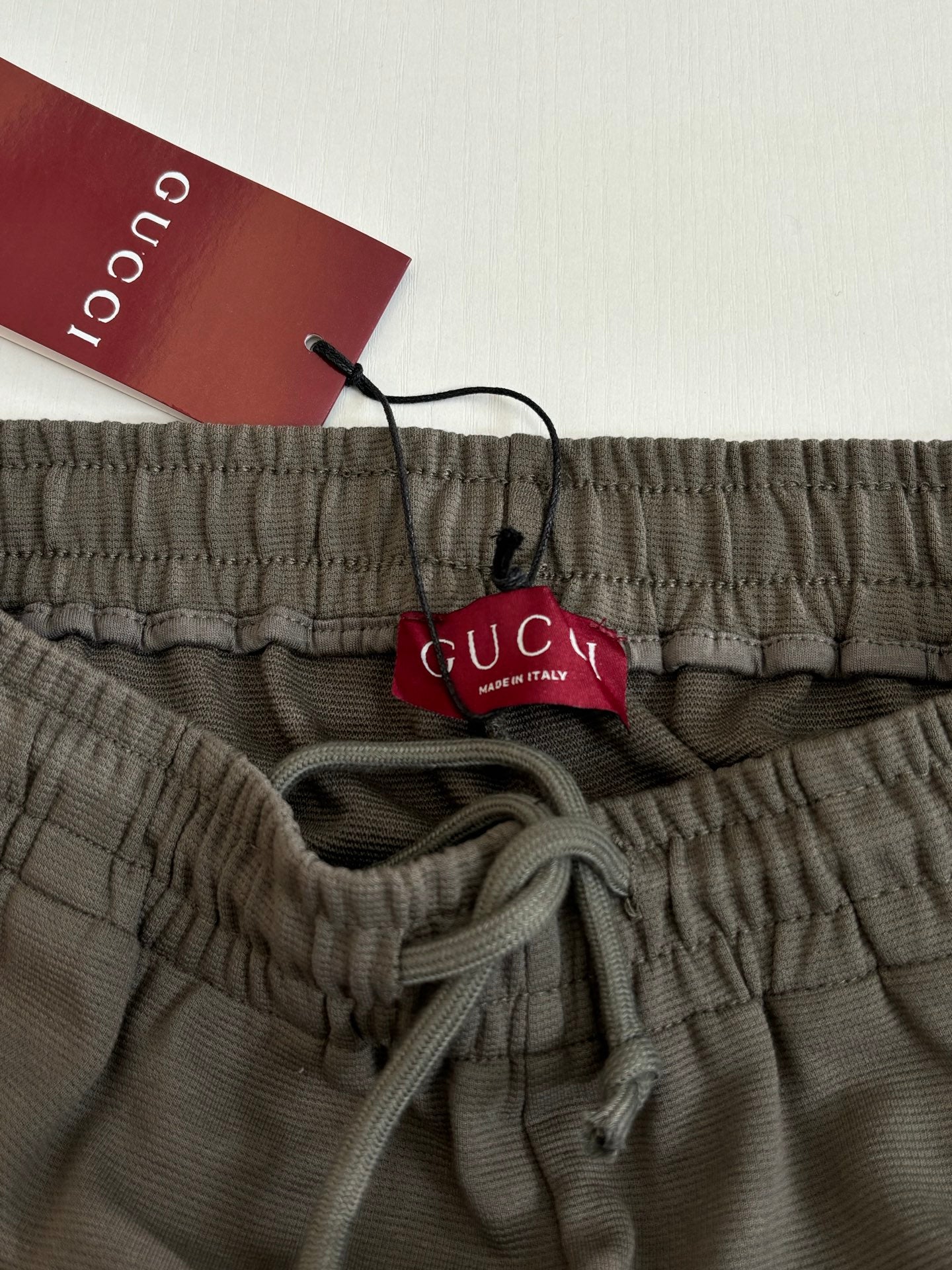 Dark gray Gucci shorts waistband with drawstring and logo; hanging brand tag