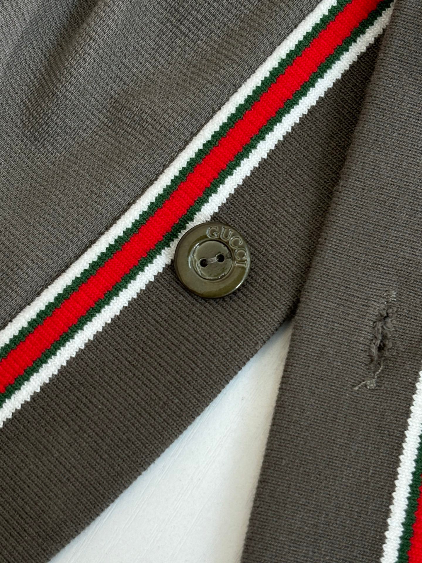 Gucci dark gray fabric close-up with red/green/white stripe and gold logo button