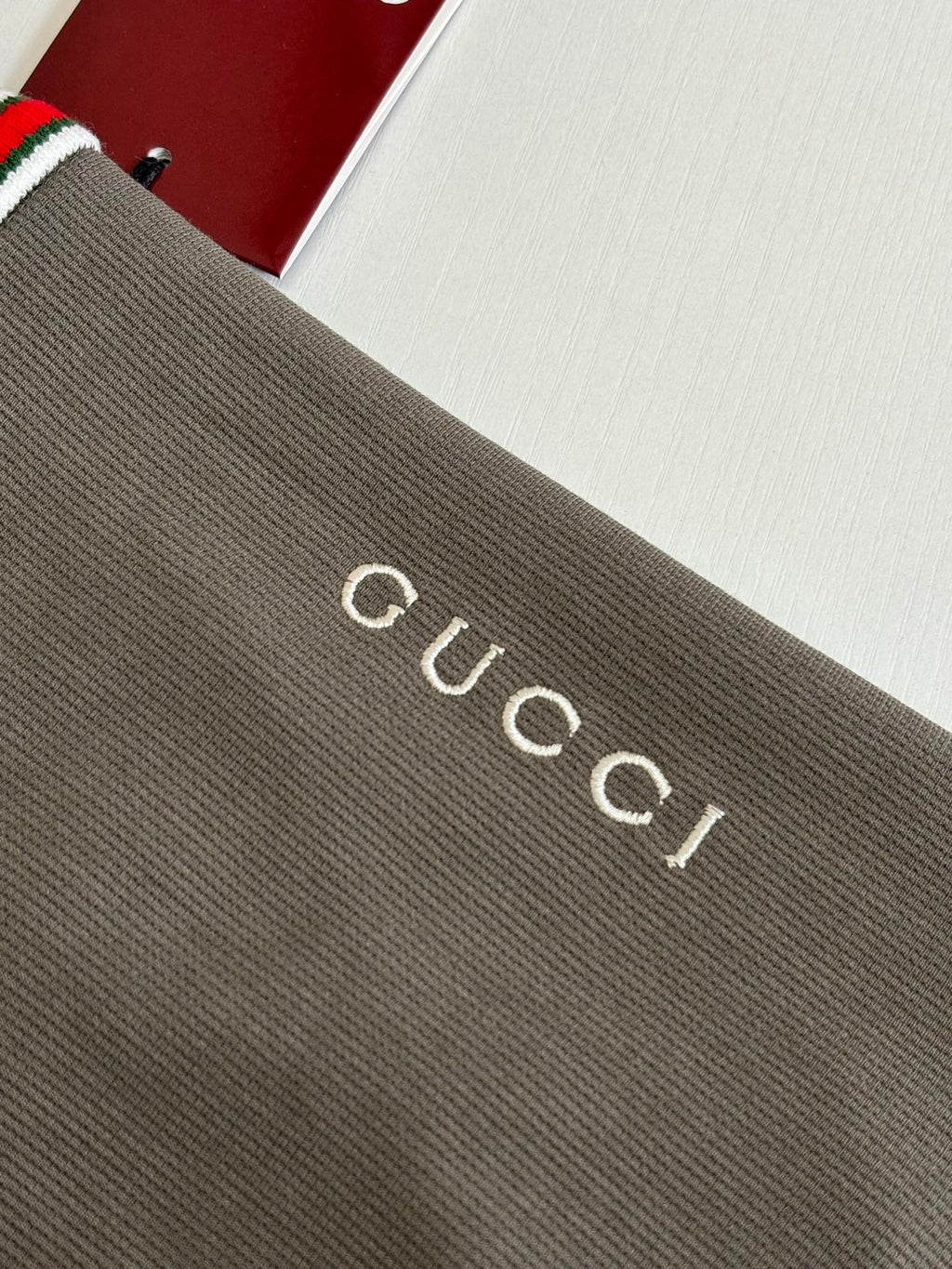 Gucci logo lettering on dark gray knit fabric of a short-sleeve shirt