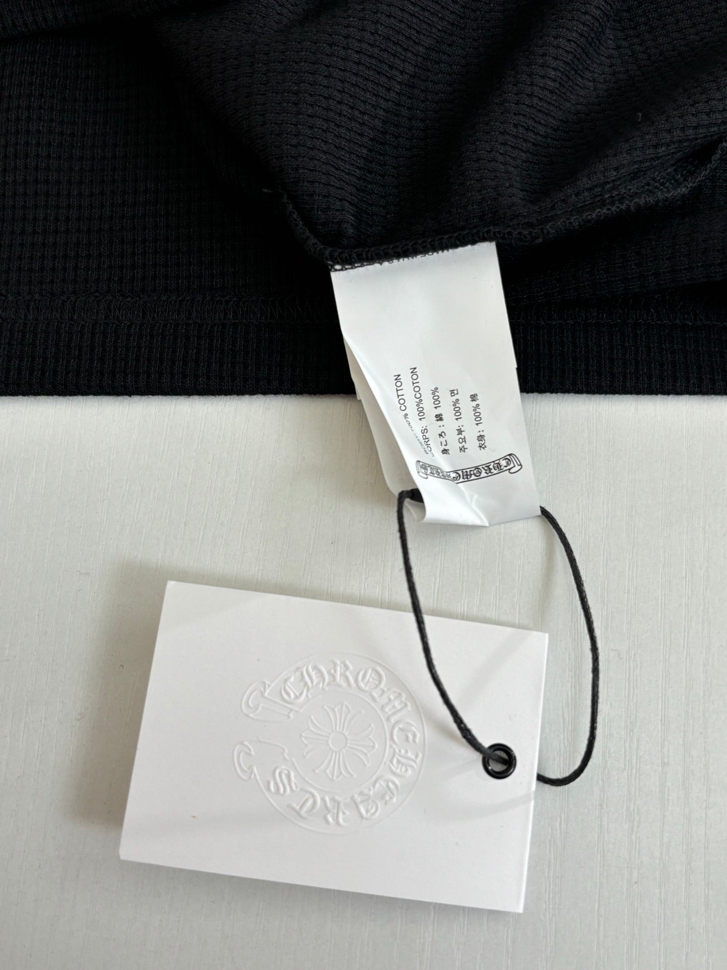 Black long-sleeve shirt with inner neck label and attached hang tags