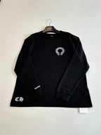 Black long-sleeve crewneck shirt with small front chest emblem and sleeve logo