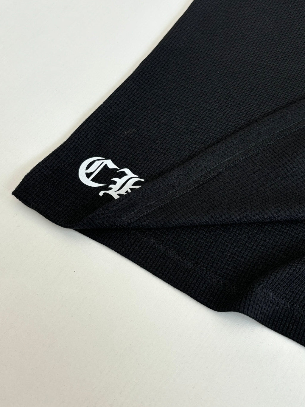 Black long-sleeve shirt sleeve cuff with small white logo print