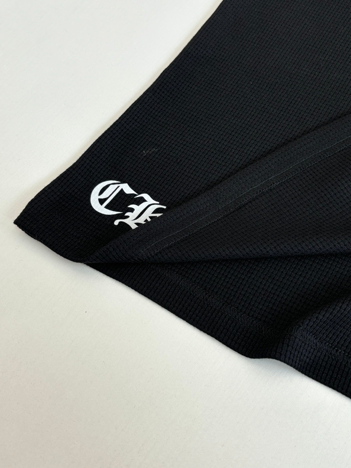 Black long-sleeve shirt sleeve cuff with small white logo print