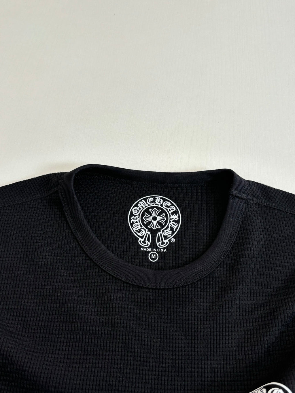 Black long-sleeve crewneck collar with round logo patch