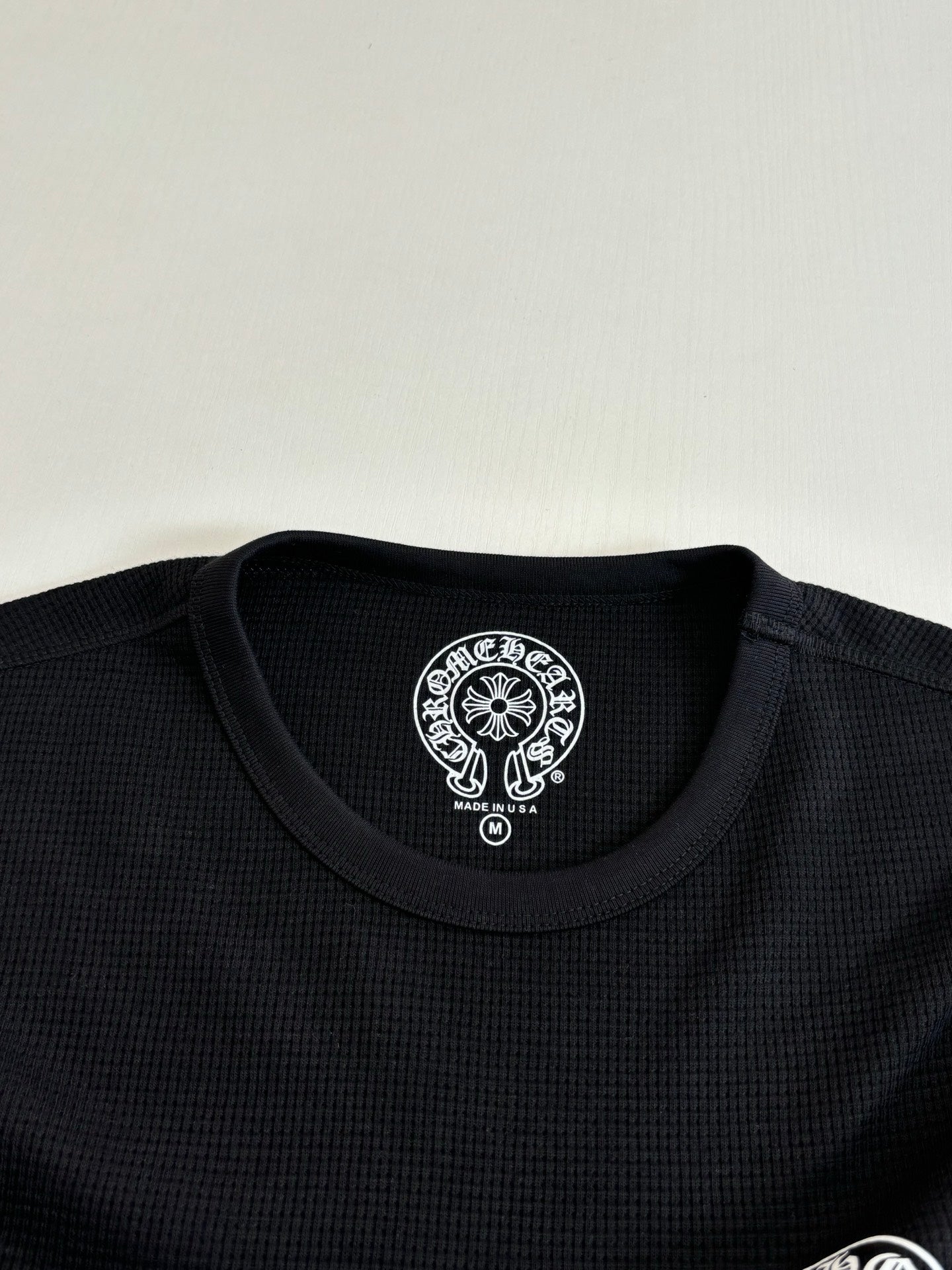 Black long-sleeve crewneck collar with round logo patch