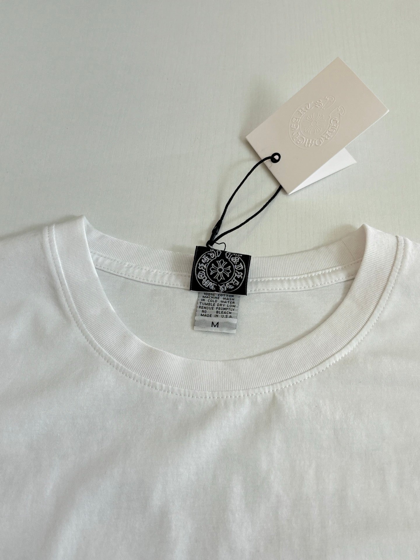 White long-sleeve T-shirt neckline with brand label and size tag.