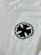White T-shirt pocket area with black cross emblem graphic.