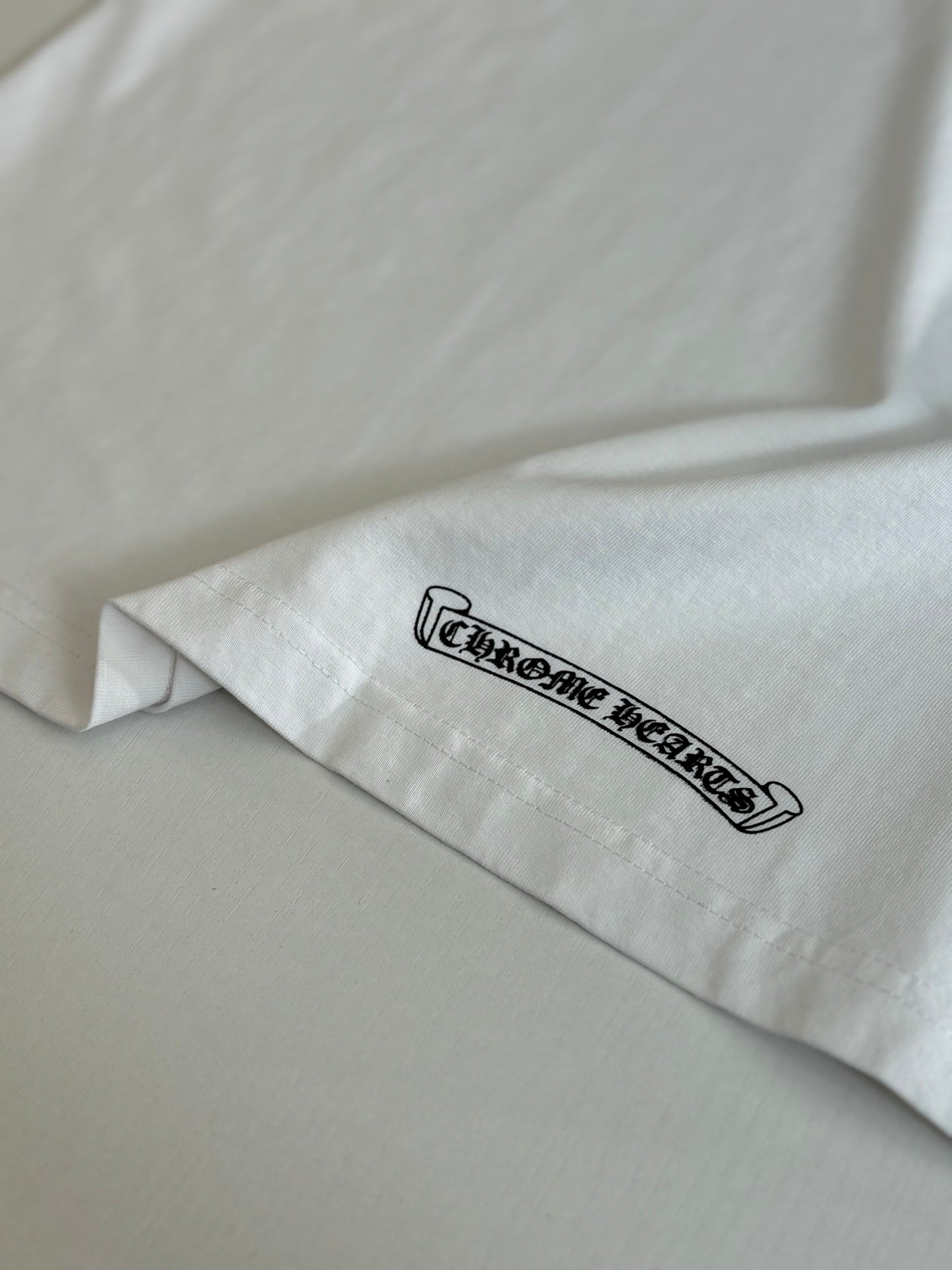 White T-shirt sleeve with black outlined logo text.