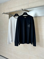 Two black and white long-sleeve crewneck tops on hangers
