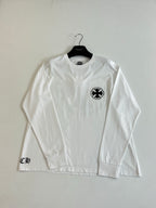 White long-sleeve T-shirt with small circular emblem on left chest.