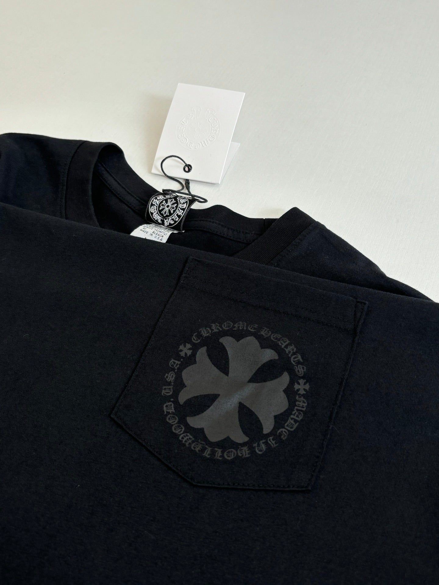 Black long-sleeve top with front logo print and woven tag