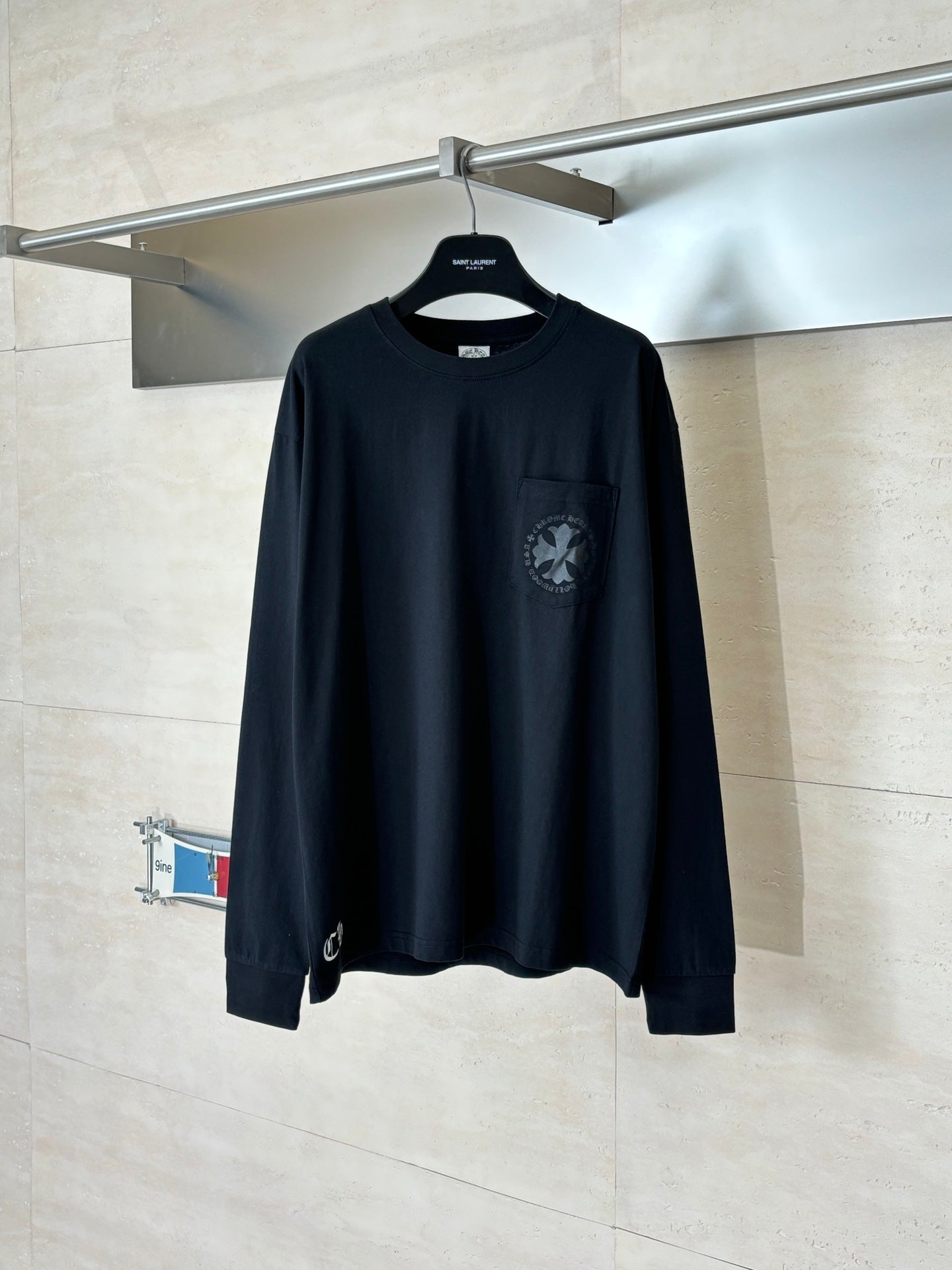 Black long-sleeve top with crew neck and chest logo graphic