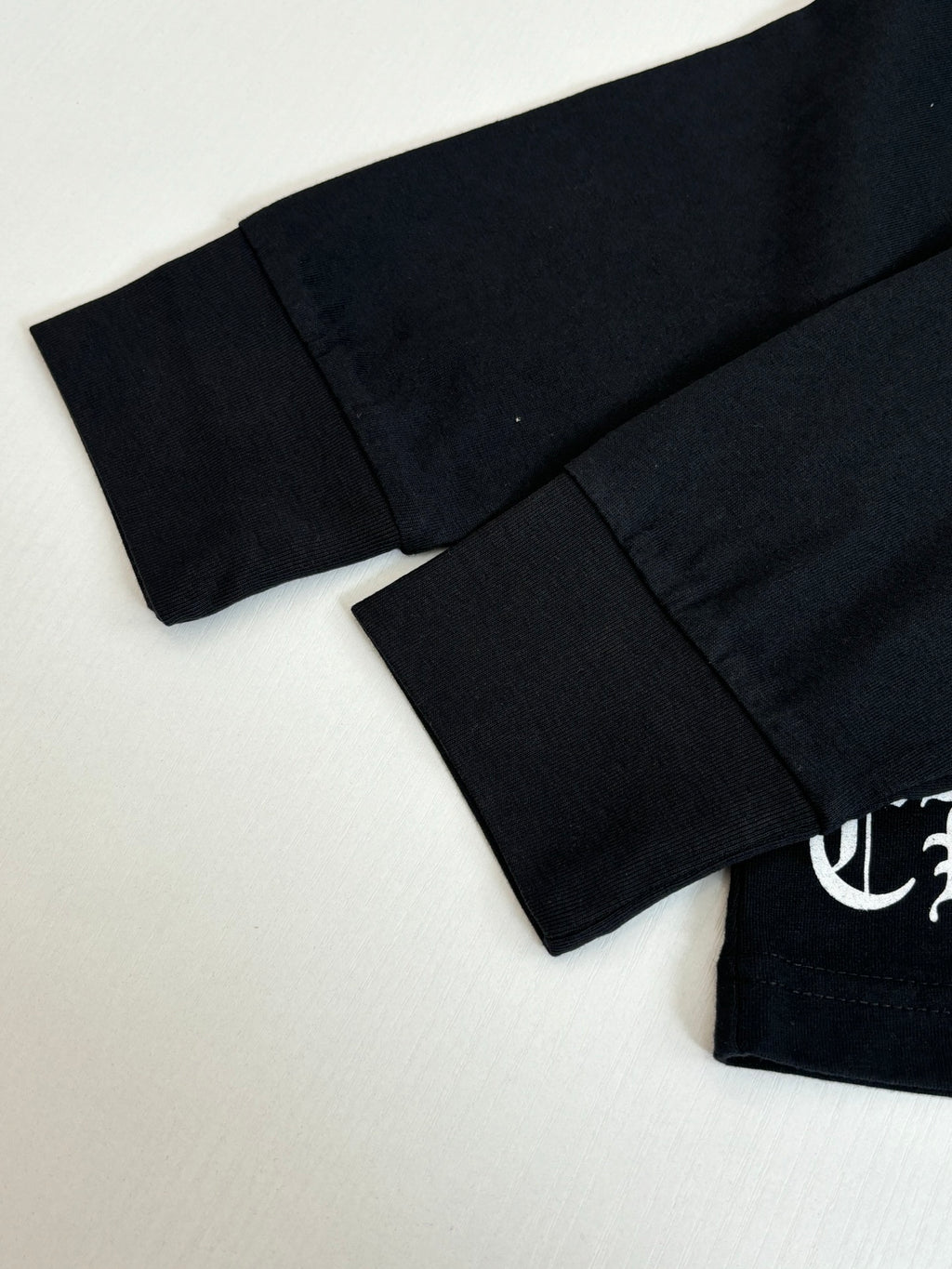 Black long-sleeve top with curved hem and partial sleeve logo