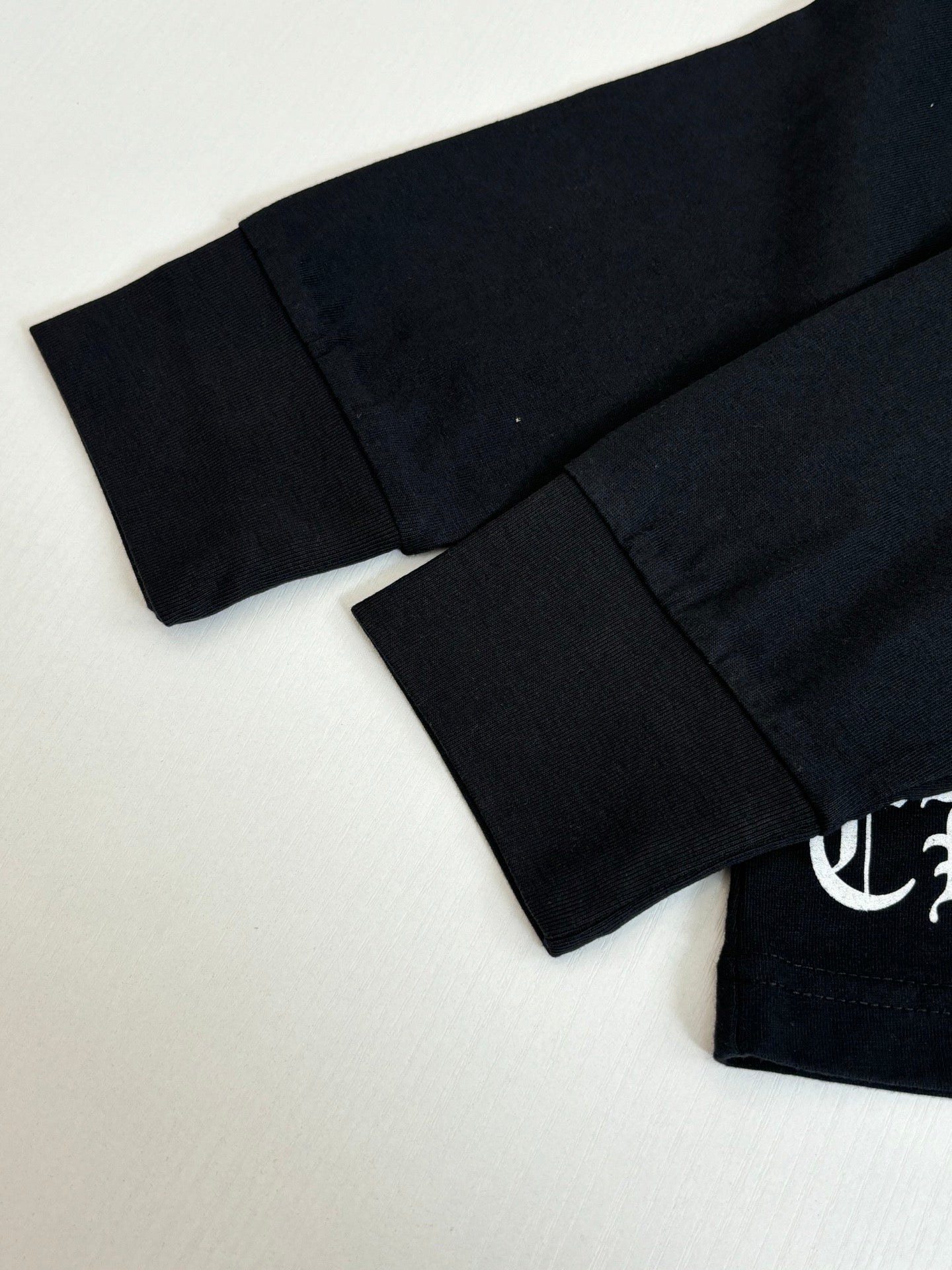 Black long-sleeve top with curved hem and partial sleeve logo