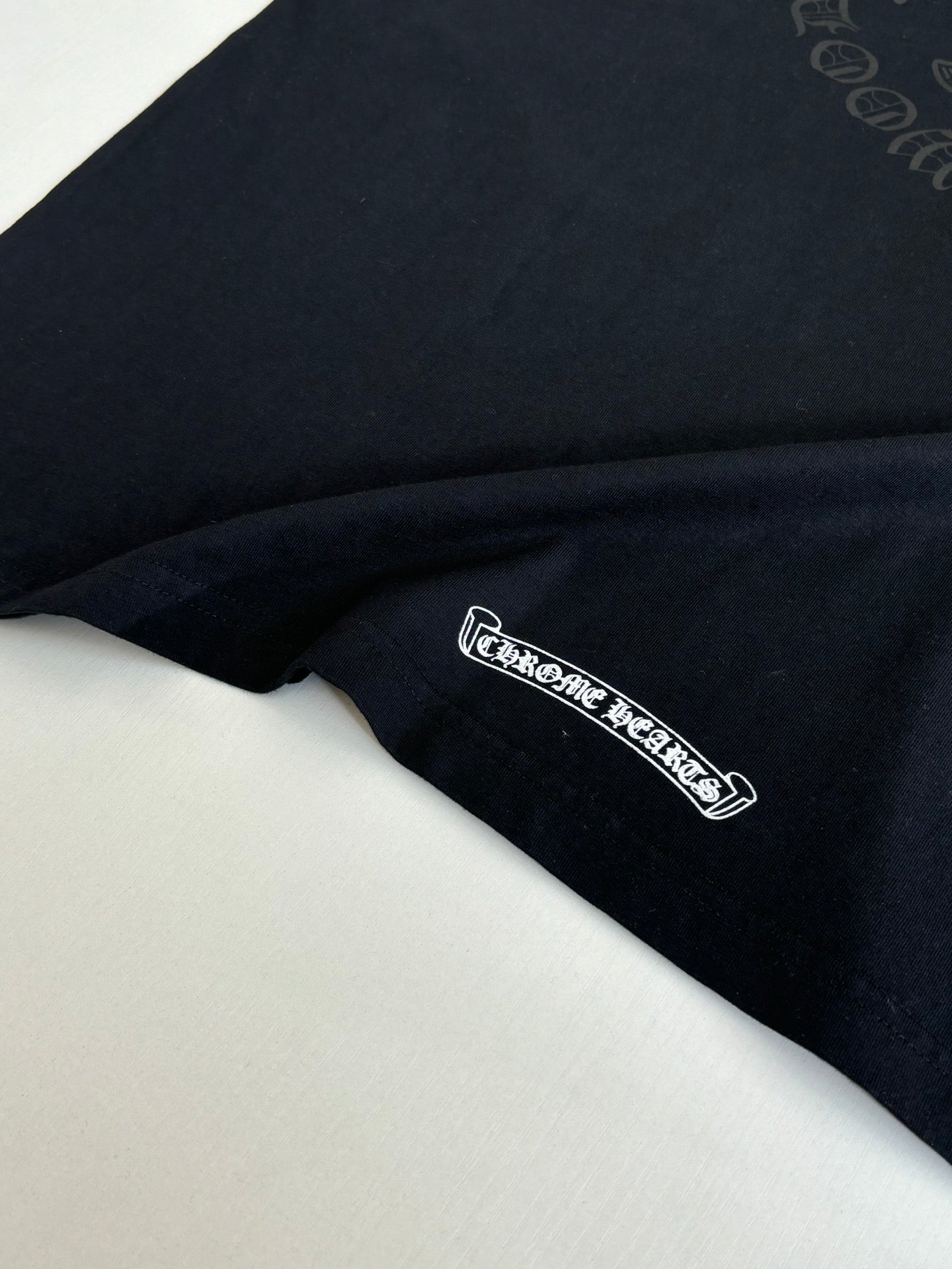 Black long-sleeve top with small embroidered logo at hem