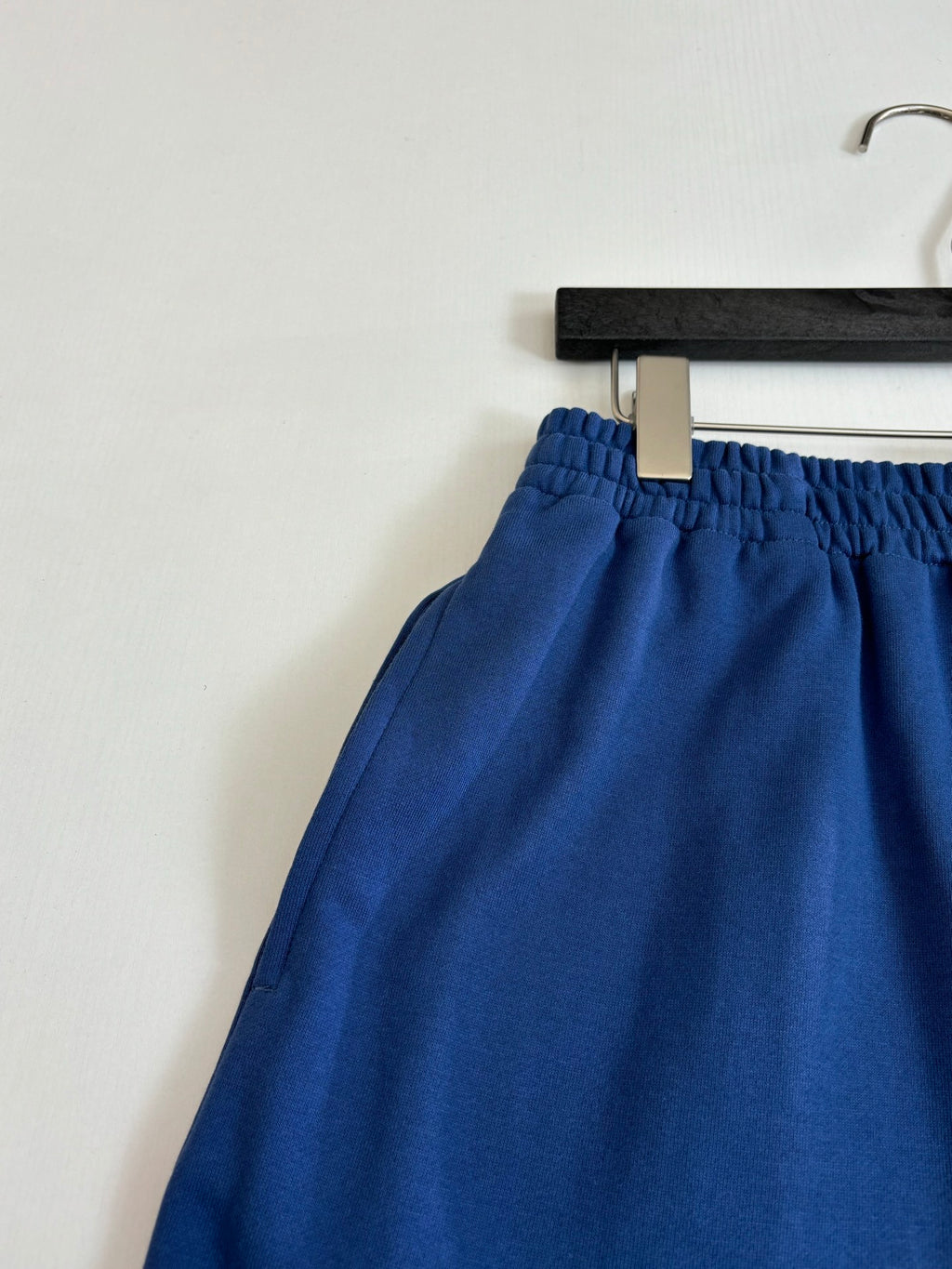Blue shorts with elastic waistband and drawstring tie, close-up on hanger