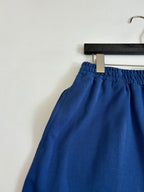 Blue shorts with elastic waistband and drawstring tie, close-up on hanger
