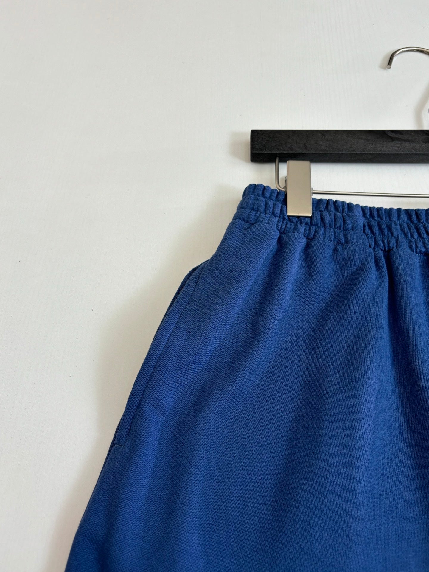 Blue shorts with elastic waistband and drawstring tie, close-up on hanger