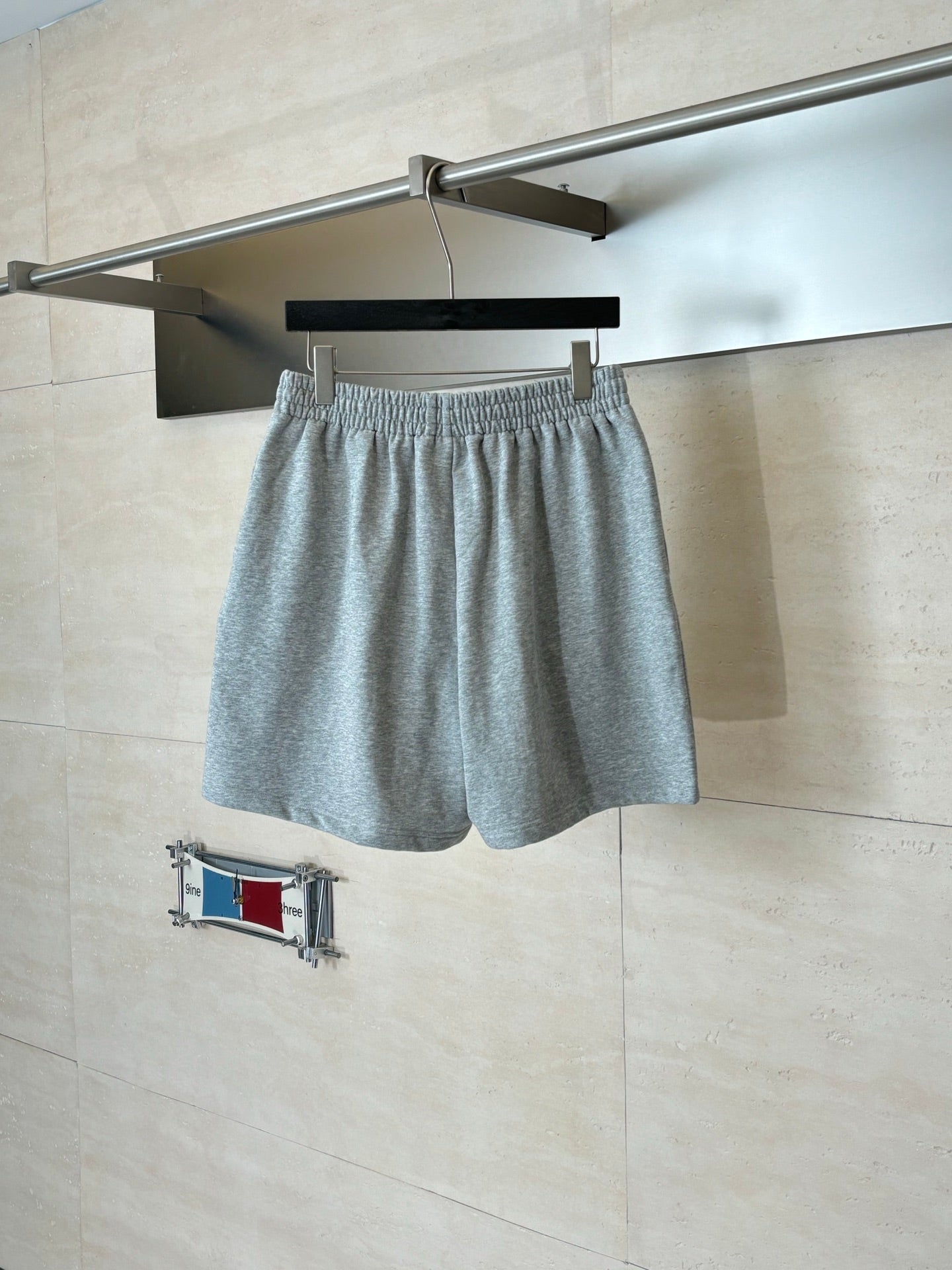 Balenciaga heather gray drawstring shorts hanging on a hanger, elastic waistband and logo