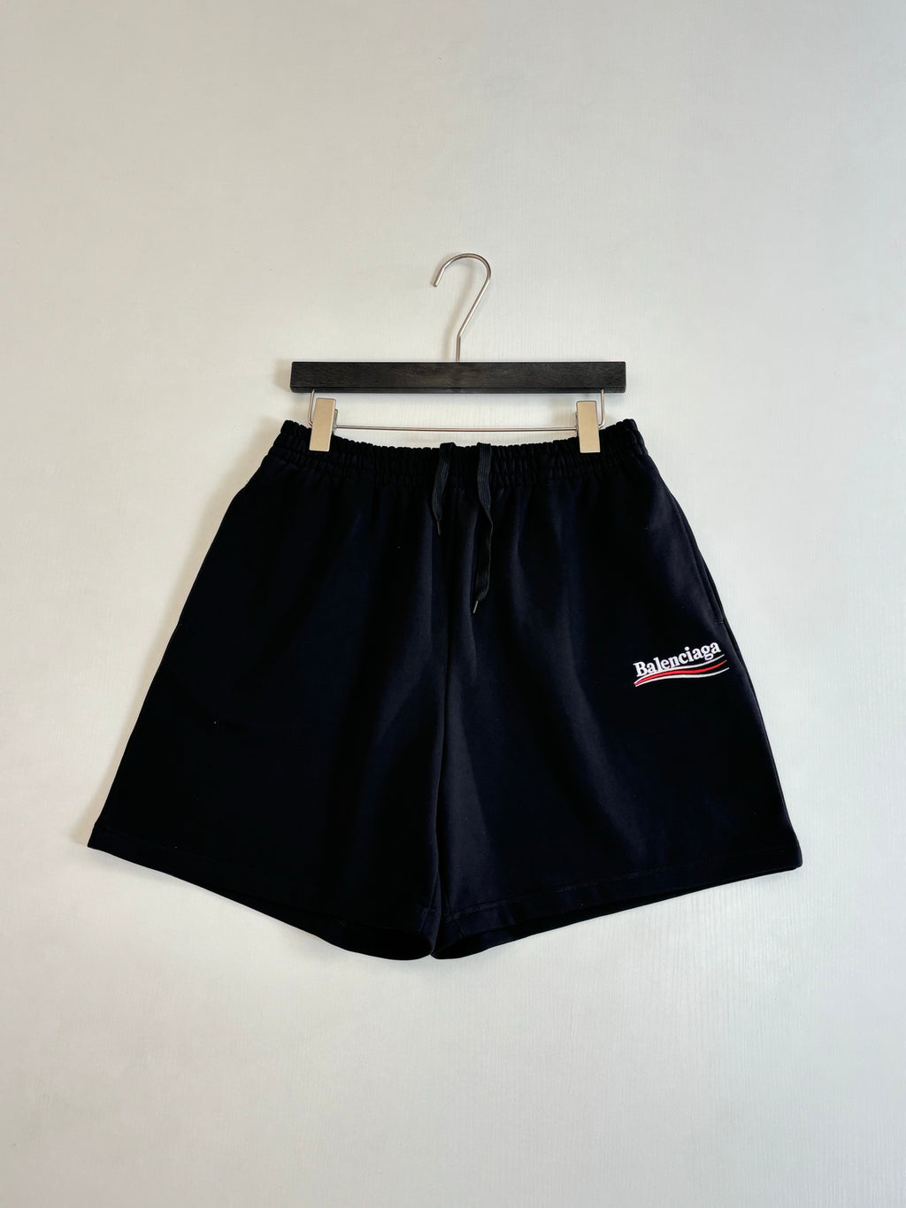 Black drawstring shorts on hanger with Balenciaga logo patch