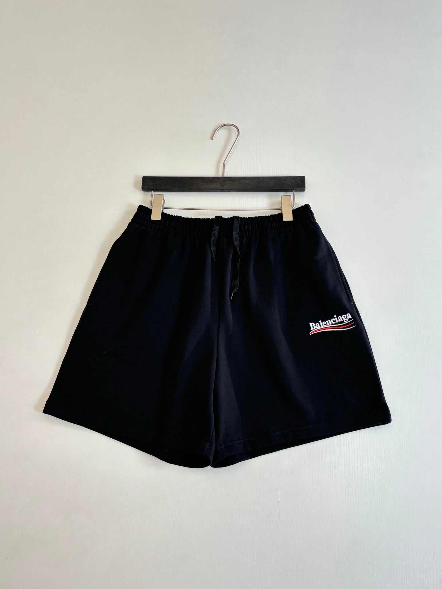 Black drawstring shorts on hanger with Balenciaga logo patch